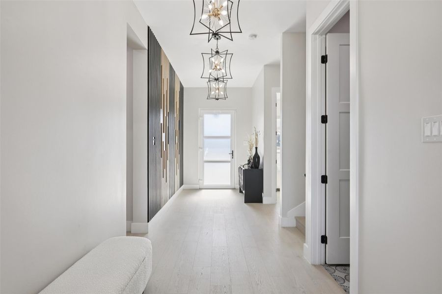 Hallway featuring hanging lights and light wood-style flooring