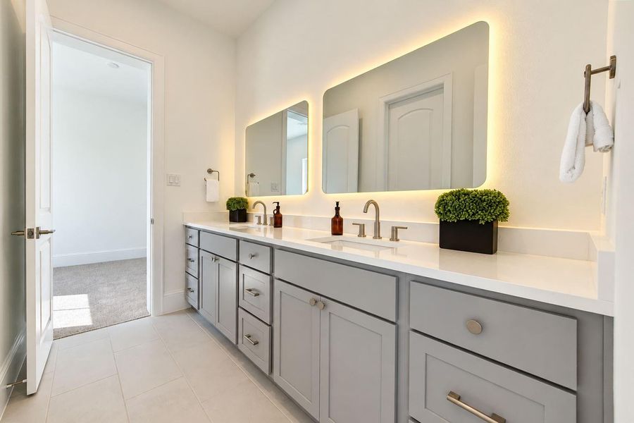 Beautifully appointed secondary bath featuring an expansive dual-sink vanity, quartz countertops, sleek cabinetry, contemporary fixtures, and illuminated mirrors. Generous storage and polished designer finishes create a sophisticated space with both style and functionality. Beautifully appointed secondary bath featuring an expansive dual-sink vanity, quartz countertops, sleek cabinetry, contemporary fixtures, and illuminated mirrors. Generous storage and polished designer finishes create a sophisticated space with both style and functionality.