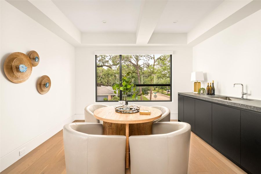 Upper-level retreat with a built-in beverage center, framed by a large picture window and treetop views.
