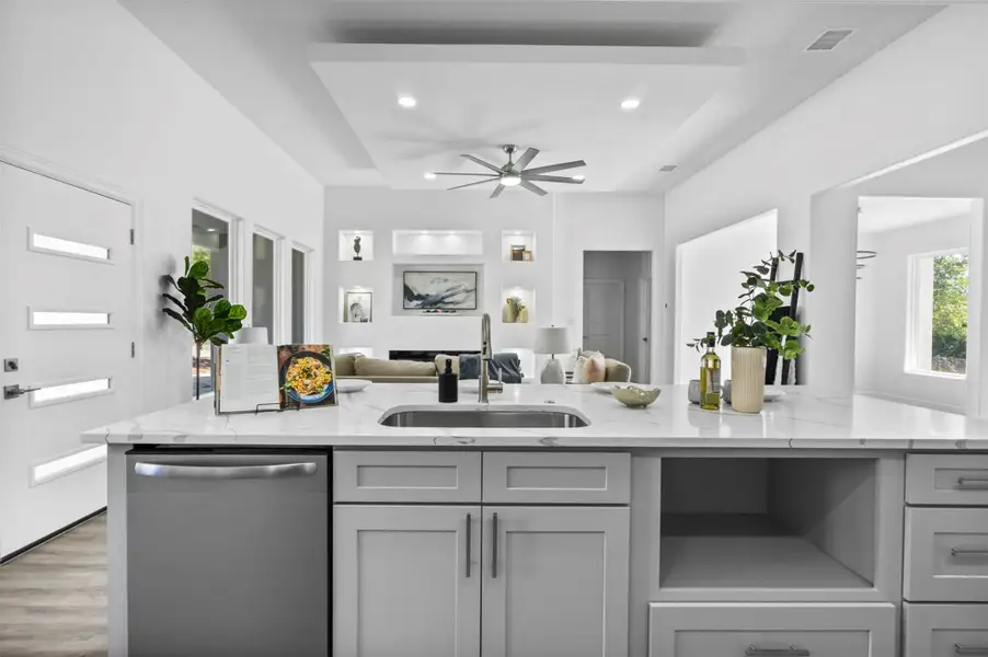 Kitchen featuring light stone counters, stainless steel dishwasher, open floor plan, a ceiling fan, and gray cabinetry