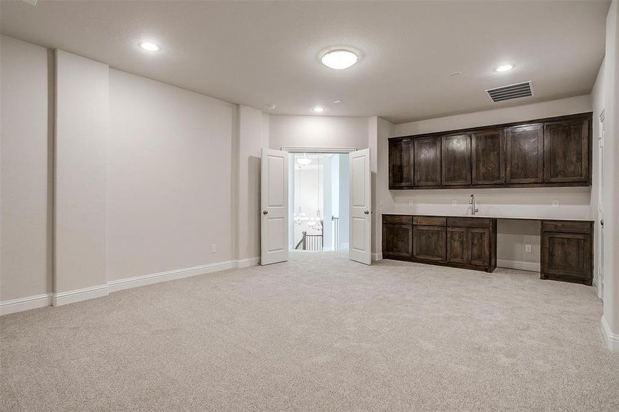 Unfurnished living room featuring built in desk and light colored carpet