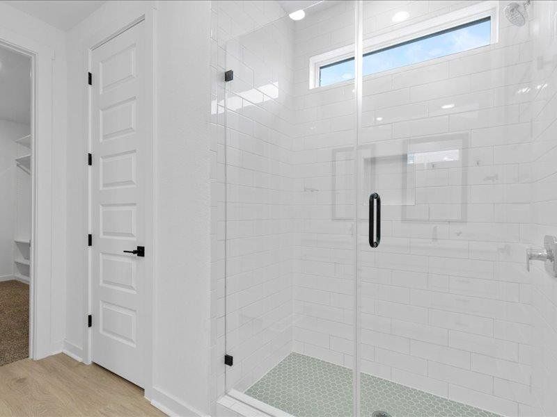 Full bath with a shower stall, light wood-style floors, and a walk in closet
