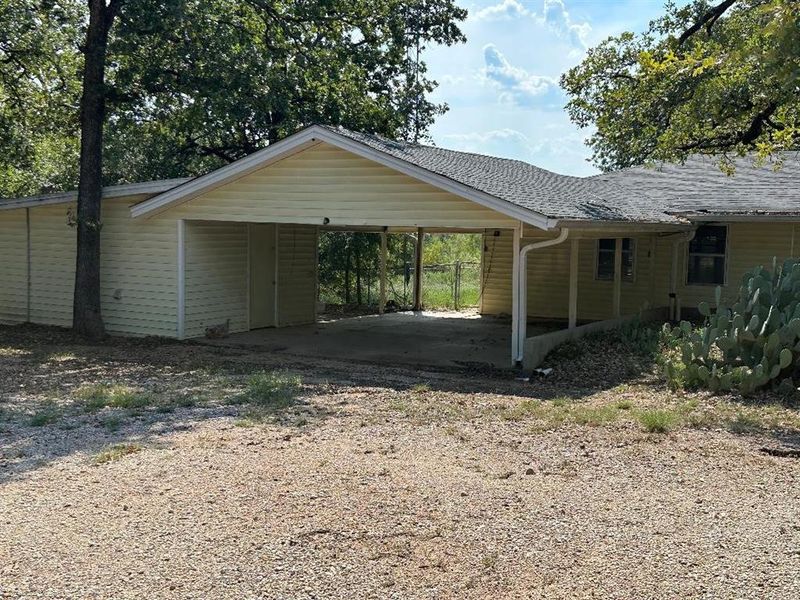 View of parking with dirt driveway and a carport