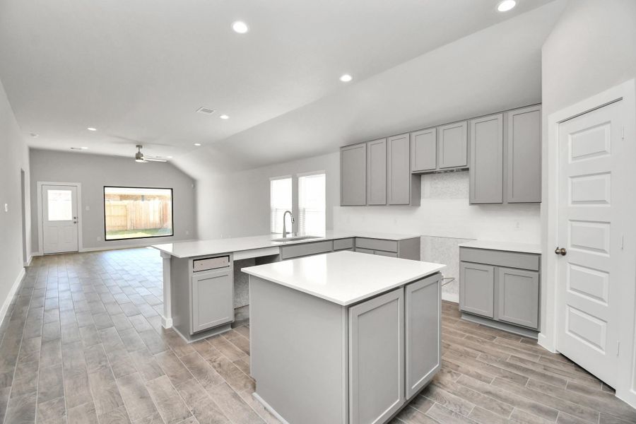 This generously spacious culinary haven features a massive granite island, high ceilings, soft-close cabinets, granite countertops, stainless steel appliances (to be installed), a sleek tile backsplash, and recessed lighting.