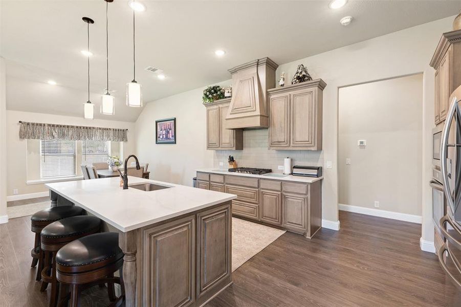 Kitchen featuring a central island with countertop seating, wood-finish flooring, recessed lighting, pendant lights, and a built-in oven and microwave Kitchen featuring a central island with countertop seating, wood-finish flooring, recessed lighting, pendant lights, and a built-in oven and microwave