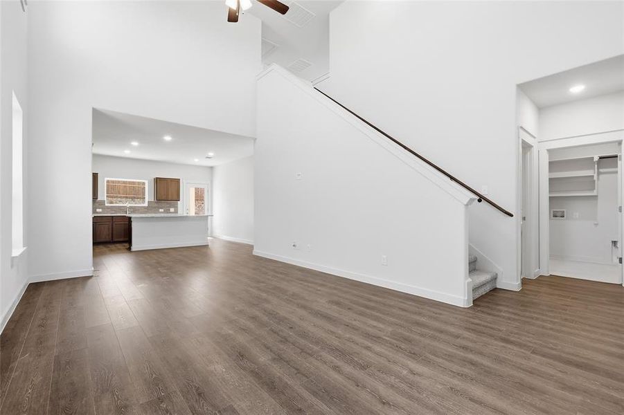 Open-concept living space featuring wood-finish flooring, high ceilings, and a contemporary ceiling fan