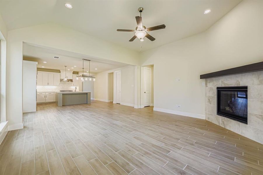 Unfurnished living room with recessed lighting, a tile fireplace, light wood-style flooring, ceiling fan, and a chandelier
