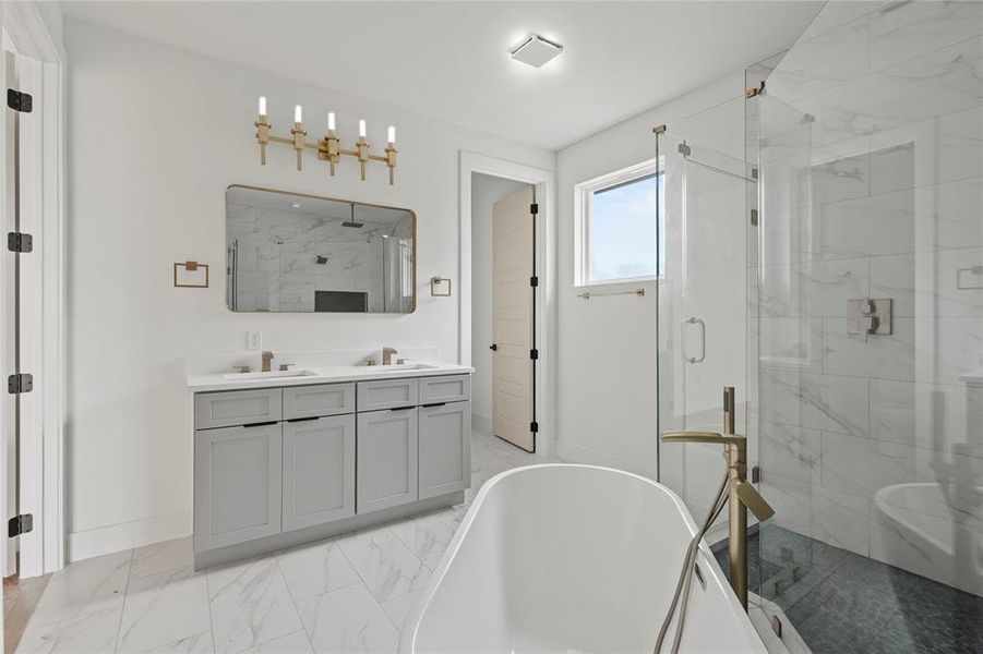 Full bath featuring double vanity, a marble finish shower, marble look tile flooring, and a freestanding bath Full bath featuring double vanity, a marble finish shower, marble look tile flooring, and a freestanding bath