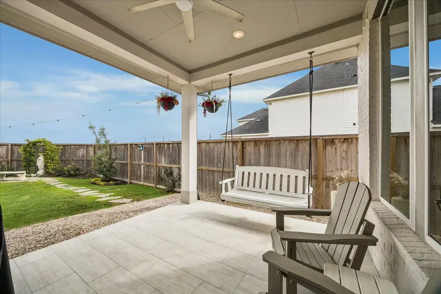 Step outside to the covered back porch featuring a charming bench swing and plenty of room for a grill and outdoor seating - perfect for relaxing or entertaining.
