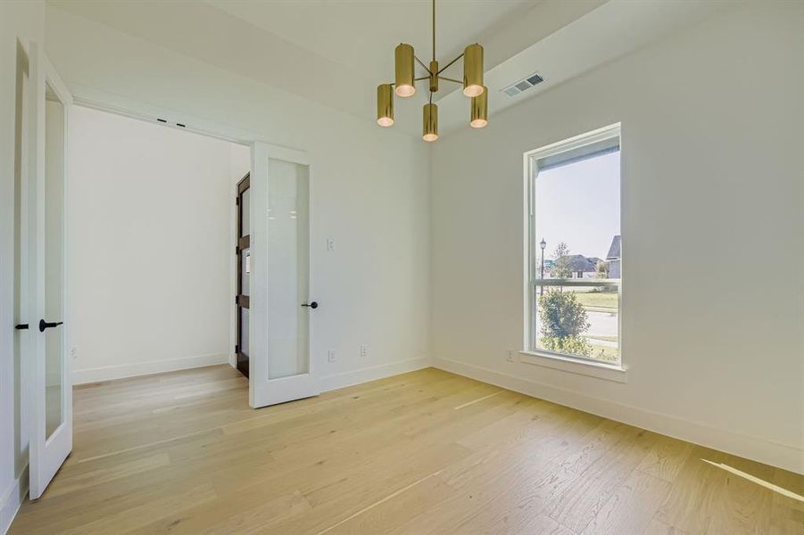 Spare room with light wood-style floors and a chandelier Spare room with light wood-style floors and a chandelier