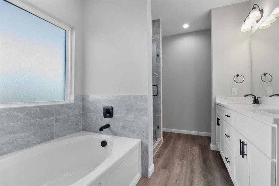 Bathroom featuring hardwood / wood-style flooring, vanity, and plus walk in shower