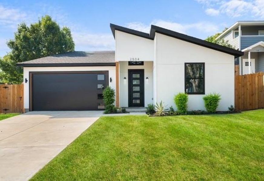 Modern home featuring an attached garage, driveway, and stucco siding Modern home featuring an attached garage, driveway, and stucco siding
