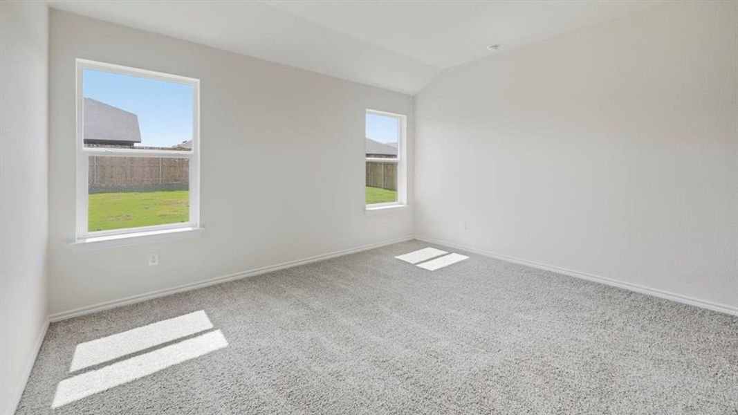 Empty room featuring light colored carpet and vaulted ceiling