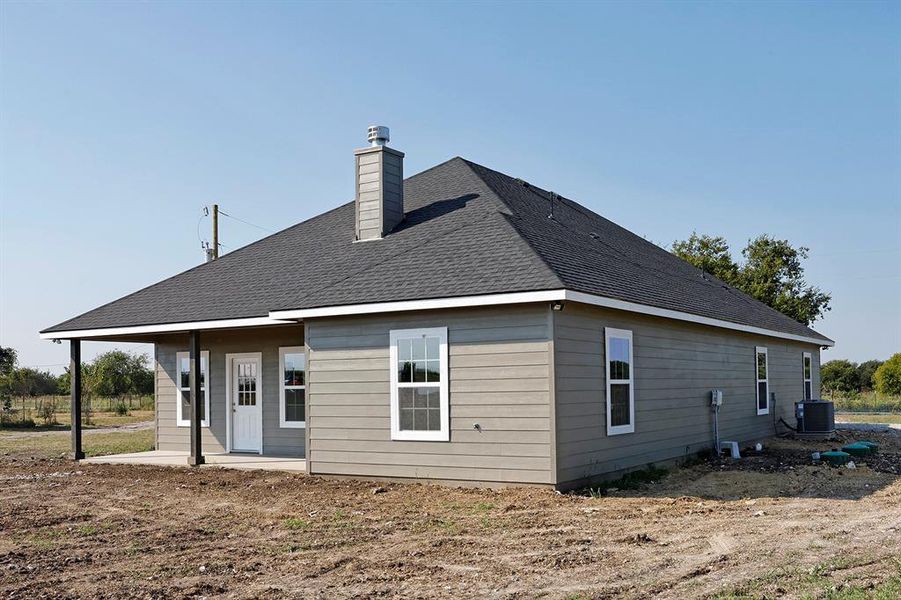 Back of property featuring roof with shingles and a chimney Back of property featuring roof with shingles and a chimney