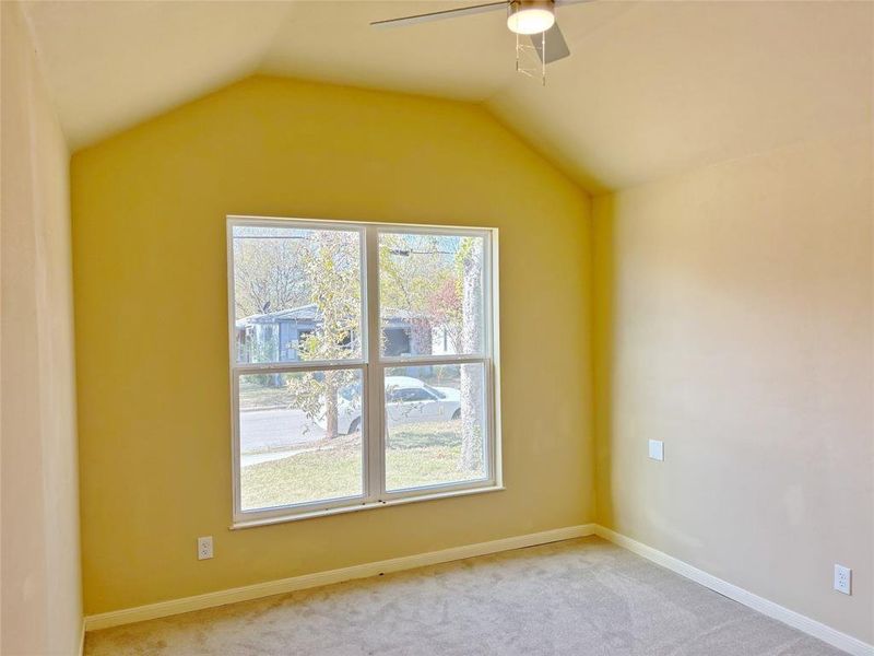 Carpeted spare room with ceiling fan and lofted ceiling