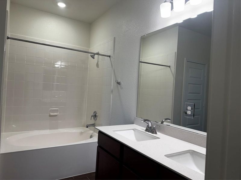 Bathroom with double vanity, a textured wall, and garden bathtub