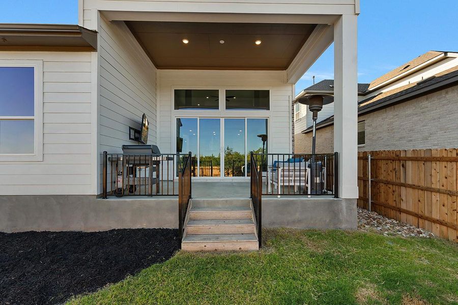 A covered back porch with concrete flooring looks out over the grassy yard.