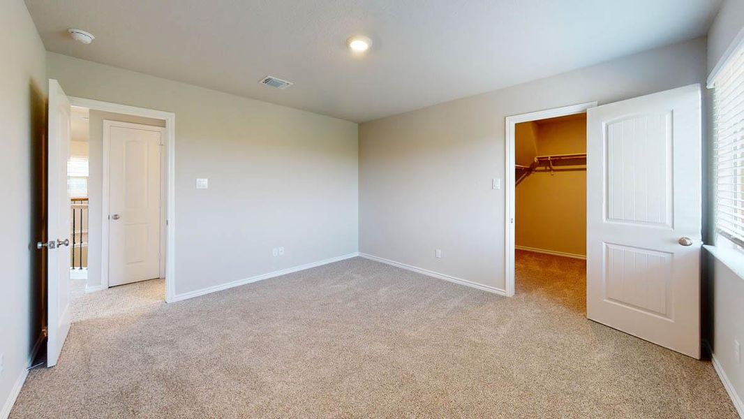 Unfurnished bedroom featuring light colored carpet and a walk in closet Unfurnished bedroom featuring light colored carpet and a walk in closet