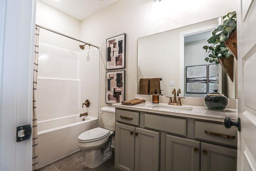Full bathroom featuring vanity, shower / tub combo, and dark tile patterned flooring
