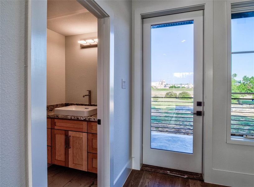 Doorway to outside with a wealth of natural light, sink, and dark hardwood / wood-style flooring