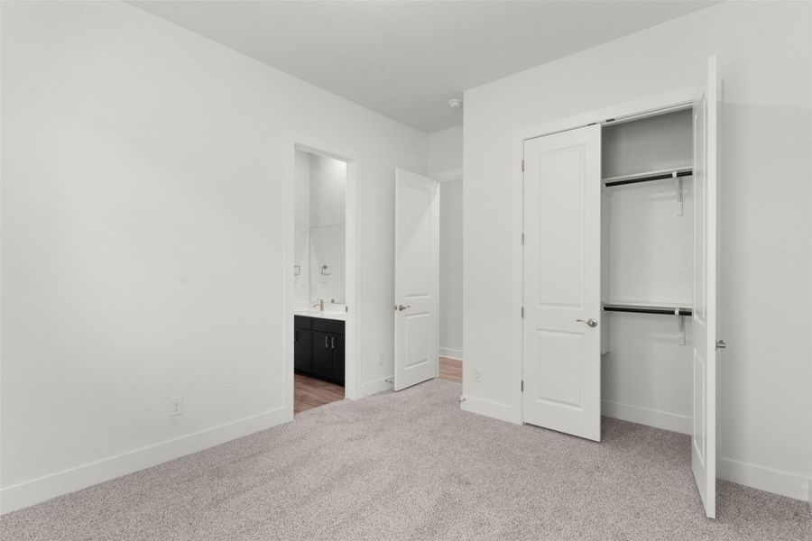 Unfurnished bedroom featuring light colored carpet, a closet, and connected bathroom