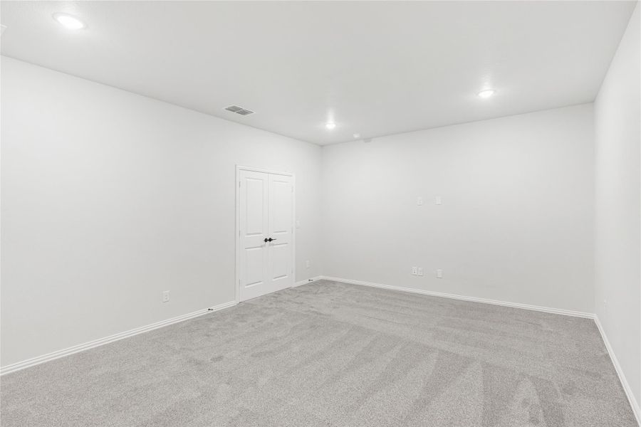 Empty bedroom with gray carpet, white walls, recessed lighting, and a double-panel closet door