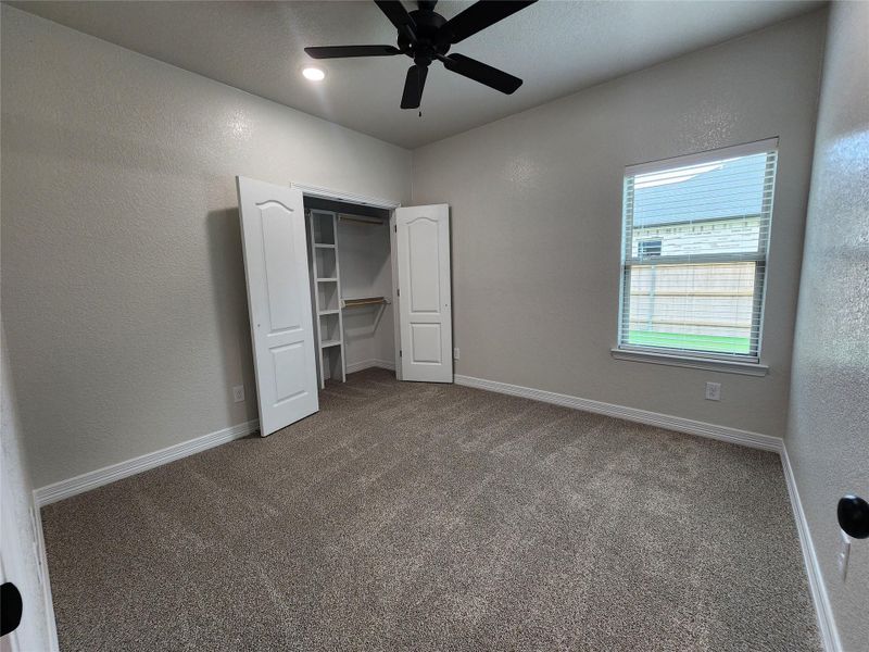 A comfortable bedroom with soft carpeting and a ceiling fan awaits relaxation. A comfortable bedroom with soft carpeting and a ceiling fan awaits relaxation.