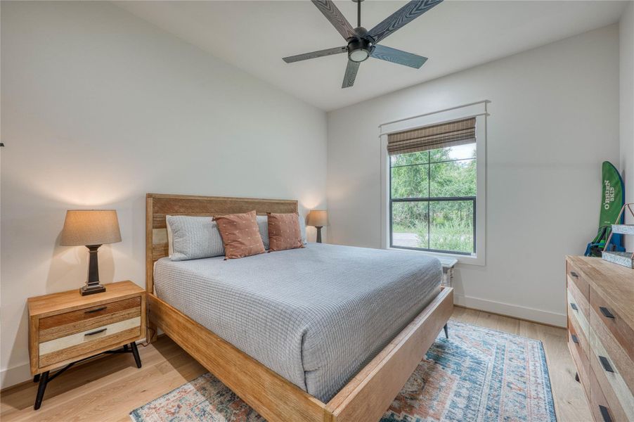 Spacious room featuring wood-finish flooring, a contemporary ceiling fan, and a large window with a woven shade
