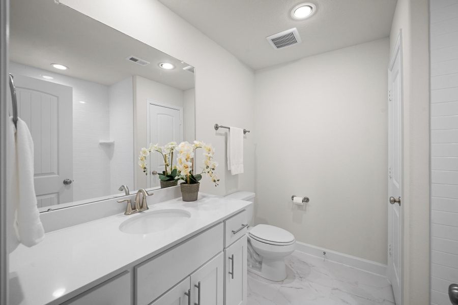 The third-floor en suite bath has a quartz vanity, undermount sink, marble-look tile floors, and a tub/shower combo — everything needed to make this floor function completely independently. The third-floor en suite bath has a quartz vanity, undermount sink, marble-look tile floors, and a tub/shower combo — everything needed to make this floor function completely independently.