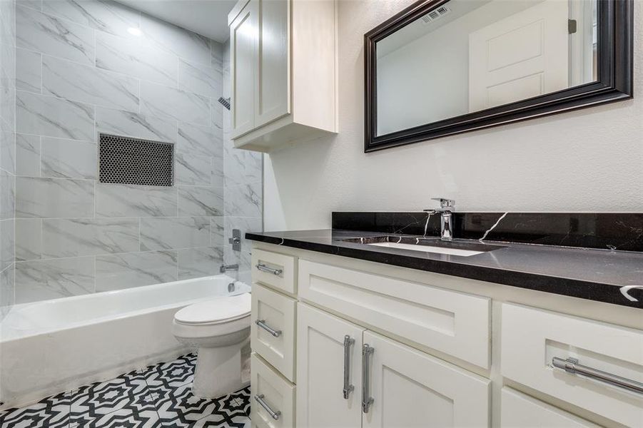 Full bathroom with tiled shower / bath, vanity, and toilet