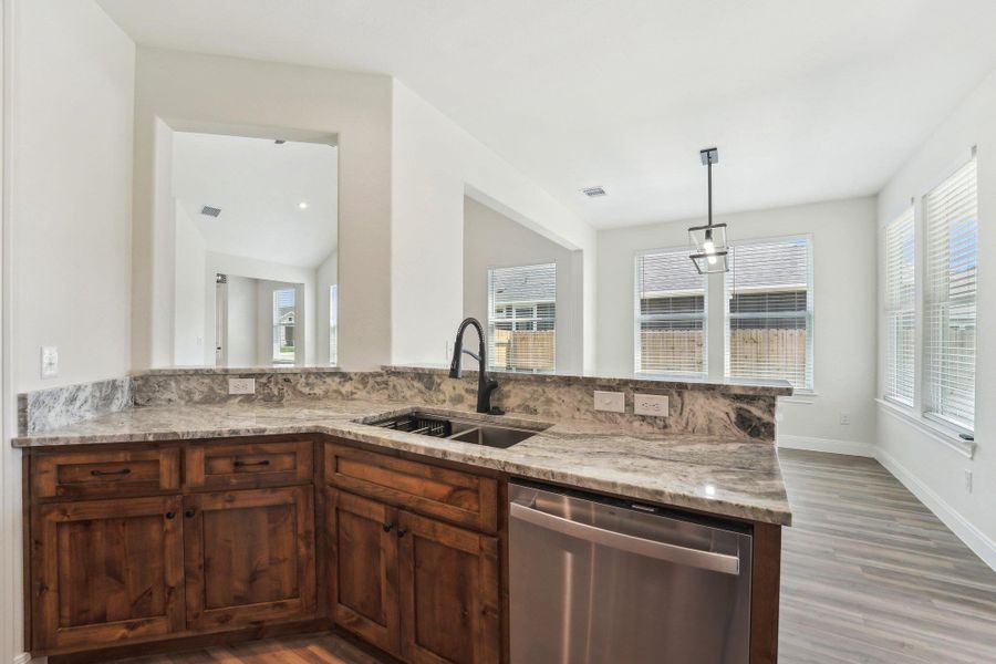 Kitchen with light stone countertops, stainless steel dishwasher, a sink, and wood-style vinyl flooring Kitchen with light stone countertops, stainless steel dishwasher, a sink, and wood-style vinyl flooring