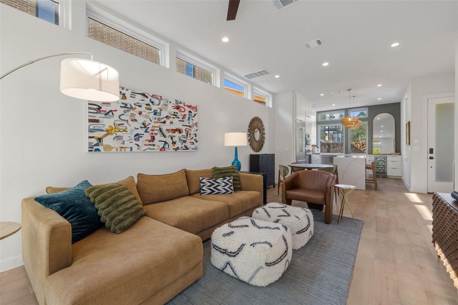 Living room featuring light wood finished floors, recessed lighting, ceiling fan, arched walkways, and wine cooler