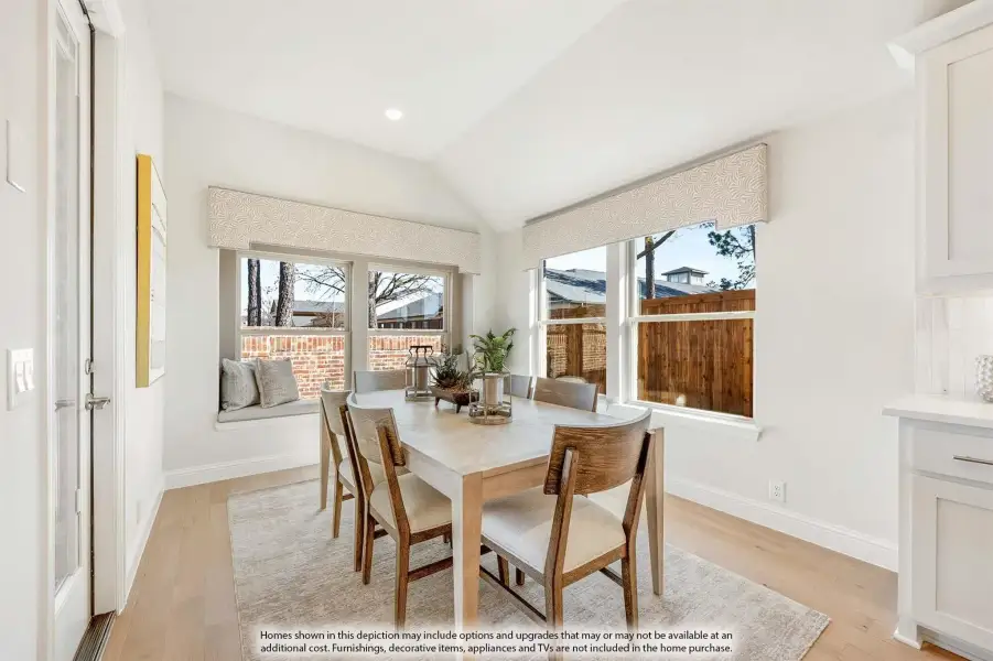 Bright dining area with wood table, six chairs, window seat, and vaulted ceiling with large windows