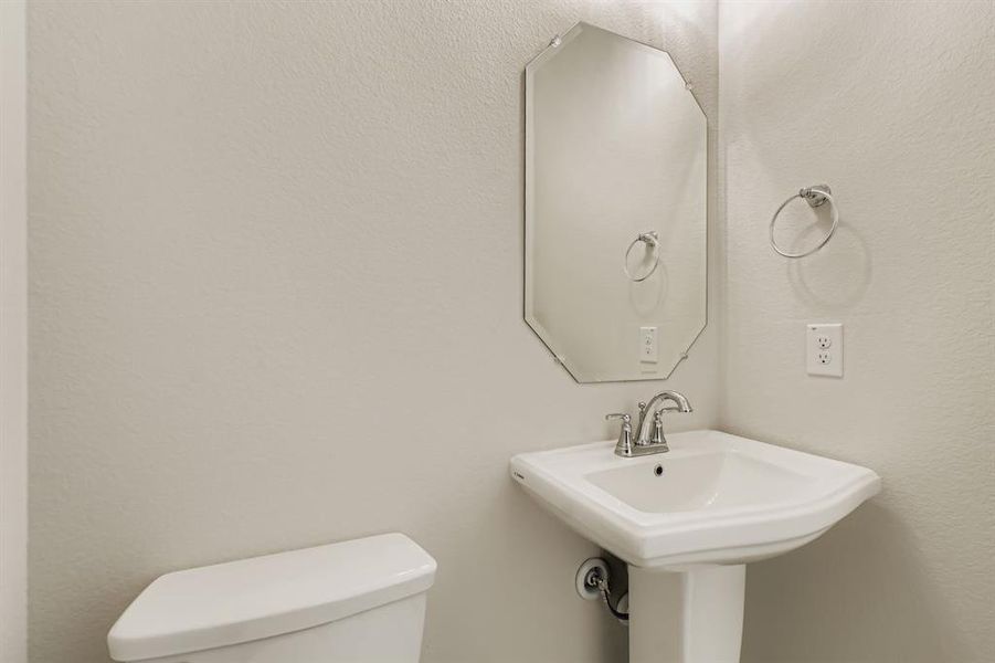 Half bathroom featuring toilet and a textured wall