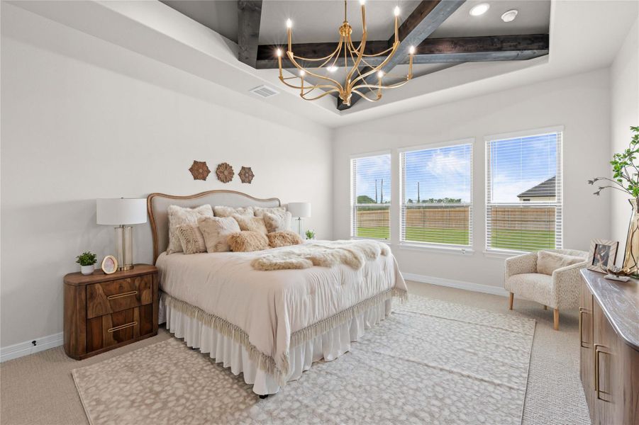 A well-lit primary bedroom features a striking coffered ceiling, elegant chandelier, and abundant natural light. A well-lit primary bedroom features a striking coffered ceiling, elegant chandelier, and abundant natural light.
