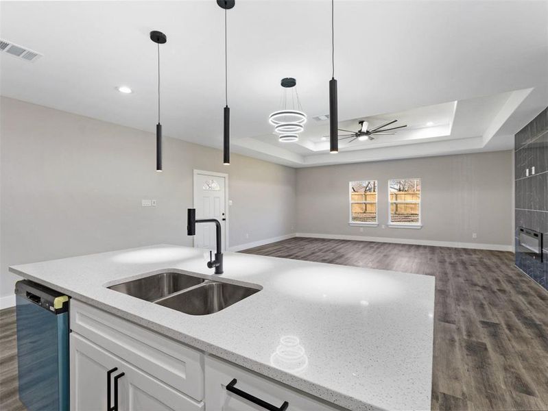 Kitchen featuring white cabinets, a tray ceiling, sink, decorative light fixtures, and dishwasher