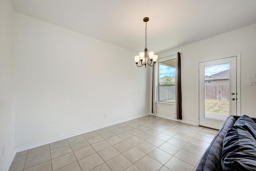 A classic chandelier illuminates this dining space with durable tile flooring and backyard access.