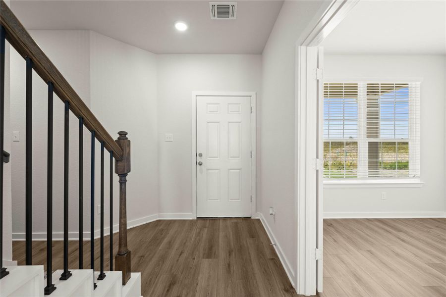 A well-lit entry hall with durable flooring and a classic staircase welcomes you home.