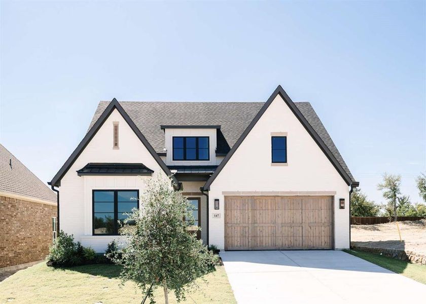 Modern farmhouse style home featuring a garage and a front yard