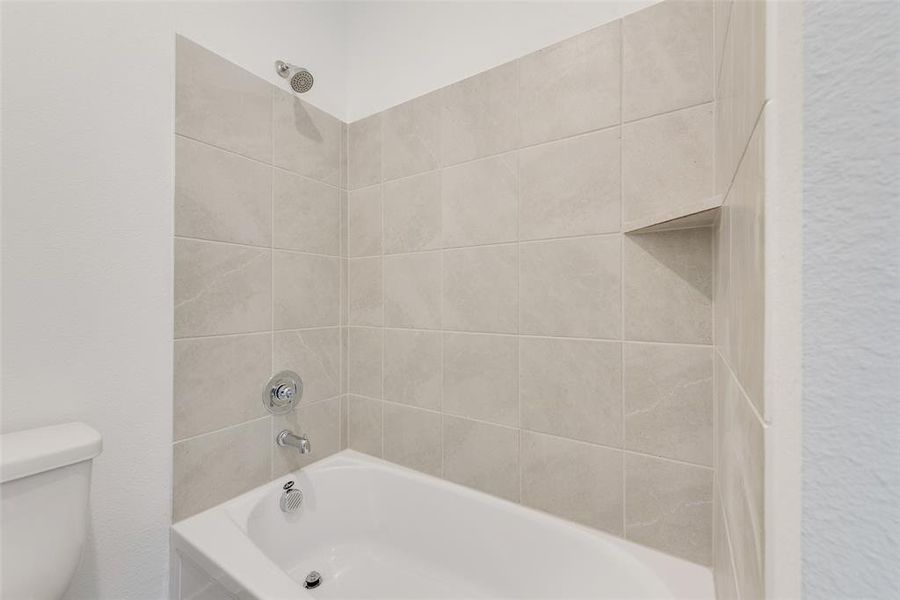 Bathroom with toilet and tiled shower / bath