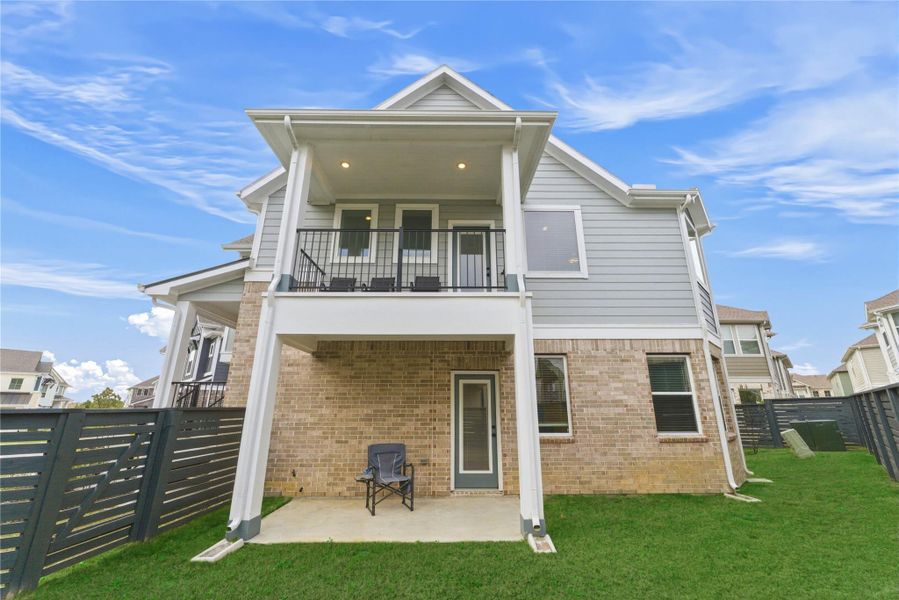 Beautiful two-story rear elevation featuring a covered patio and private balcony, perfect for enjoying outdoor living on both levels.