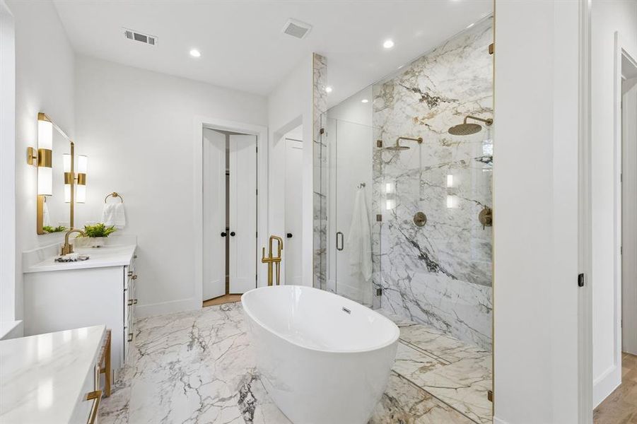 Bathroom featuring vanity, a freestanding tub, a marble finish shower, recessed lighting, and light marble finish floors