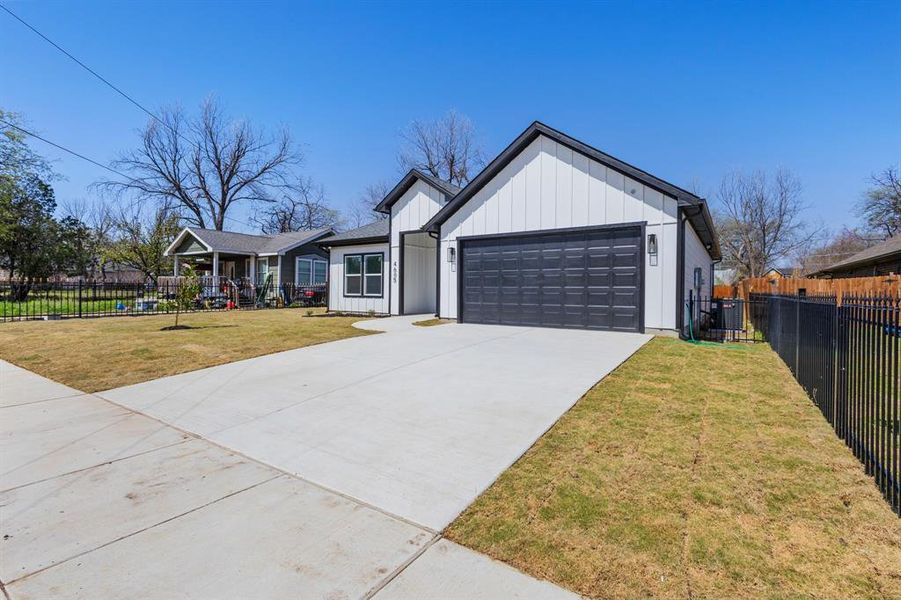 Modern farmhouse style home with concrete driveway, an attached garage, fence, and board and batten siding