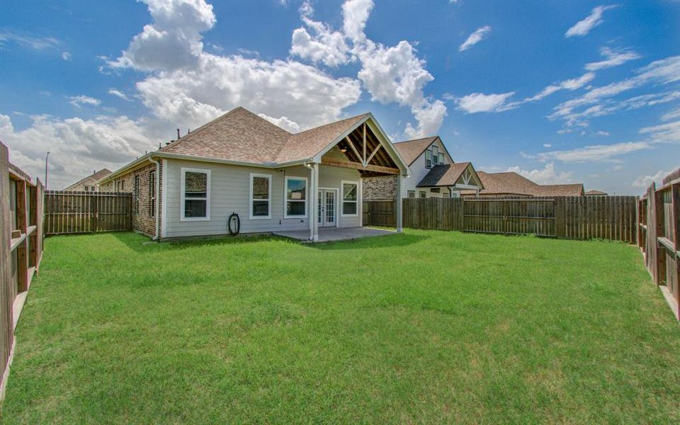 Charming single-story home featuring a spacious backyard with a privacy fence and a covered patio area, perfect for outdoor living and entertaining. The exterior showcases a combination of brick and siding, with ample natural light and an inviting entryway.