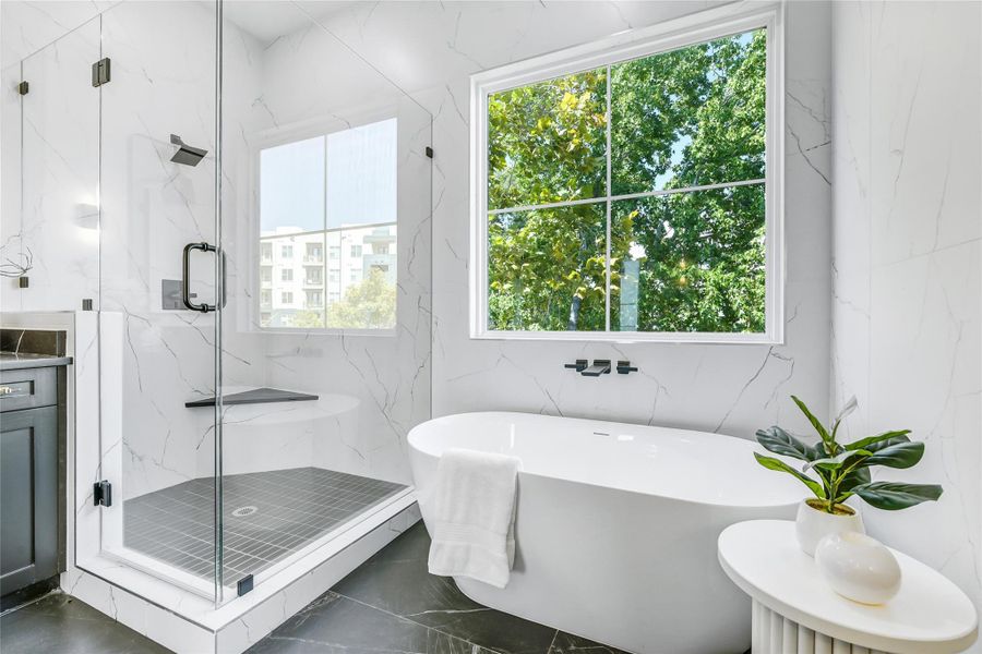 A sculptural freestanding soaking tub anchors this elegant space, framed by large energy-efficient windows that invite soft natural light. Surrounded by book-matched marble-look walls and a serene palette, this bath embodies the perfect retreat for medical professionals seeking peace, rejuvenation, and a touch of modern luxury. A sculptural freestanding soaking tub anchors this elegant space, framed by large energy-efficient windows that invite soft natural light. Surrounded by book-matched marble-look walls and a serene palette, this bath embodies the perfect retreat for medical professionals seeking peace, rejuvenation, and a touch of modern luxury.