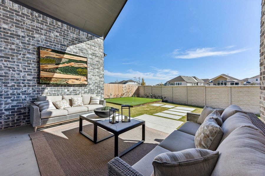 Sheltered by a vaulted patio ceiling, this brick-walled outdoor living area overlooks a manicured putting green.