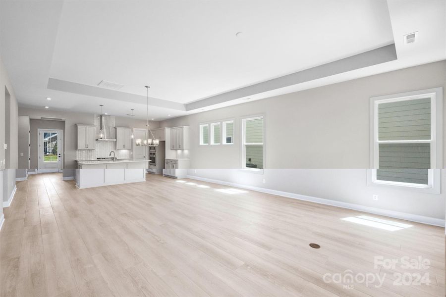 Great Room with EVP Flooring, Tray Ceiling, and Floor Outlet with Brass Trim