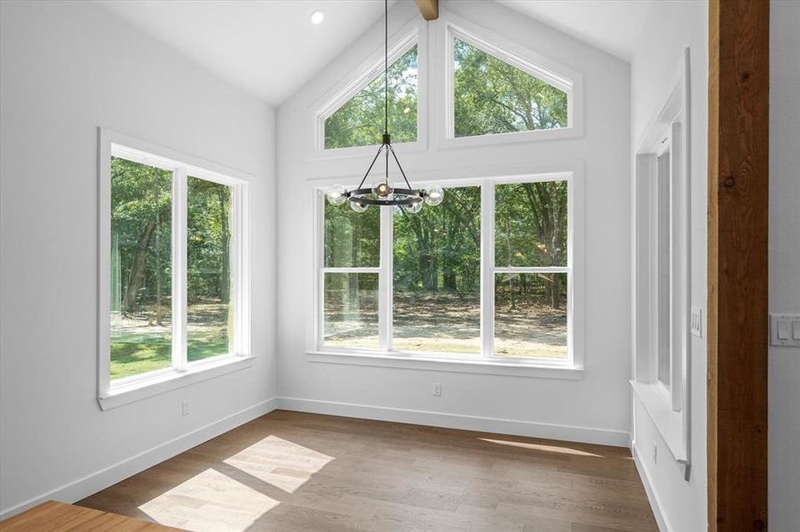 Unfurnished dining area with wood finished floors, a chandelier, and vaulted ceiling Unfurnished dining area with wood finished floors, a chandelier, and vaulted ceiling