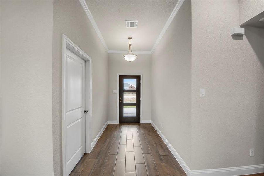Hallway featuring wood-finish tile flooring, a two-panel interior door, and crown molding