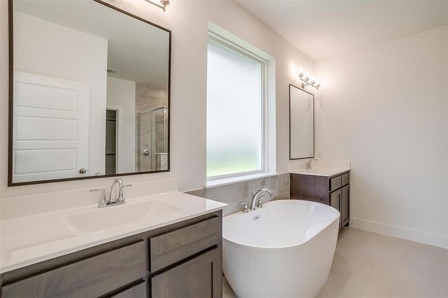 Bathroom with tile flooring, a bath, and double vanity